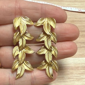 Orecchini pendenti a foglia color oro con texture botanica e chiusura a perno.