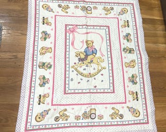 Manta infantil vintage con diseño de osito de peluche y caballito mecedora, color rosa y azul, color blanco.