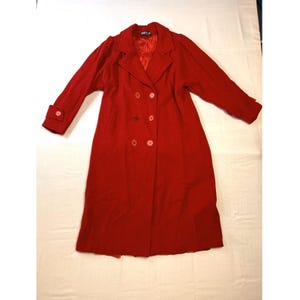 May include: A long, red double-breasted coat. The coat has a notched collar, six buttons, and long sleeves with buttoned cuffs. The coat is made of a solid red fabric and has a red lining. The coat's length is approximately 120 cm.