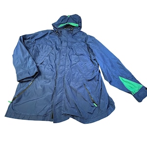 May include: A navy blue hooded jacket with a green interior lining and green sleeve accents. The jacket features a zip closure and multiple pockets. The jacket is made of a lightweight, water-resistant material.