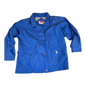 May include: A vibrant blue jacket with a collared neckline and a button-up front. The jacket features two front pockets and a ribbed hem. The interior collar lining has a striped pattern. A small tag is visible on the collar.