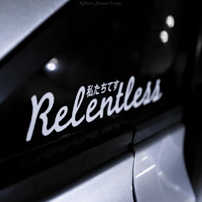Pode incluir: Um carro preto com um adesivo branco que diz "Relentless" em uma fonte estilizada. O texto japon&ecirc;s acima da palavra "Relentless" diz "私達です".