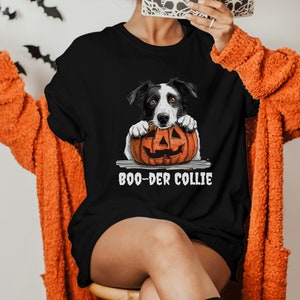 May include: A black t-shirt with a graphic of a black and white border collie dog holding a jack-o-lantern. The text "BOO-DER COLLIE" is printed below the dog.