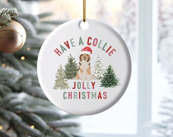 May include: Round white Christmas ornament with a Collie dog wearing a Santa hat in a snowy forest scene. The text reads "Have a Collie Jolly Christmas".