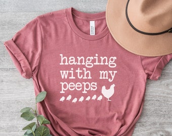 May include: A heather mauve t-shirt with the text "hanging with my peeps" and a white chicken with chicks graphic.
