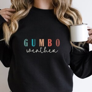 May include: Black sweatshirt with the text "GUMBO weather" in colorful letters. The letters are in shades of blue, teal, orange, red, and pink.