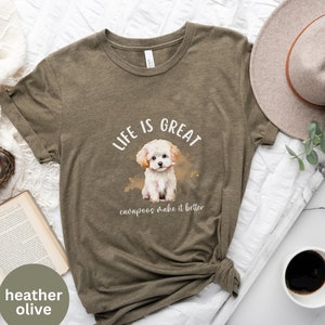 May include: A heather olive t-shirt with a watercolor illustration of a white cavapoo puppy. The text "Life is Great cavapoos make it better" is printed on the shirt.
