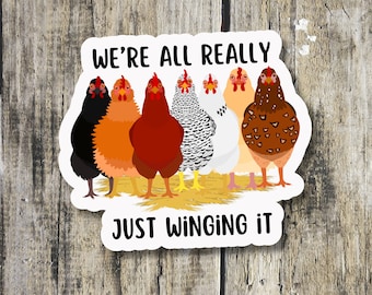 May include: A white sticker with a group of six chickens in a row. The chickens are all different colors and breeds. The text "We're all really just winging it" is written in black letters on the sticker.