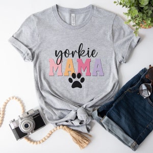 May include: Gray t-shirt with the text "yorkshire mama" in colorful letters and a black paw print.