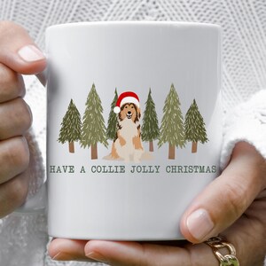 May include: White ceramic mug with a Christmas design. The mug features a collie dog wearing a Santa hat, surrounded by green Christmas trees. The text "HAVE A COLLIE JOLLY CHRISTMAS" is printed below the image.