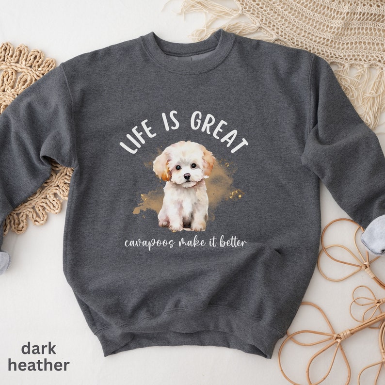 K&ouml;nnte beinhalten: Dunkelgrauer Sweatshirt mit einem wei&szlig;en Aquarellbild eines Cavapoo-Welpen. Der Text "Life is Great, cavapoos make it better" ist auf dem Sweatshirt aufgedruckt.