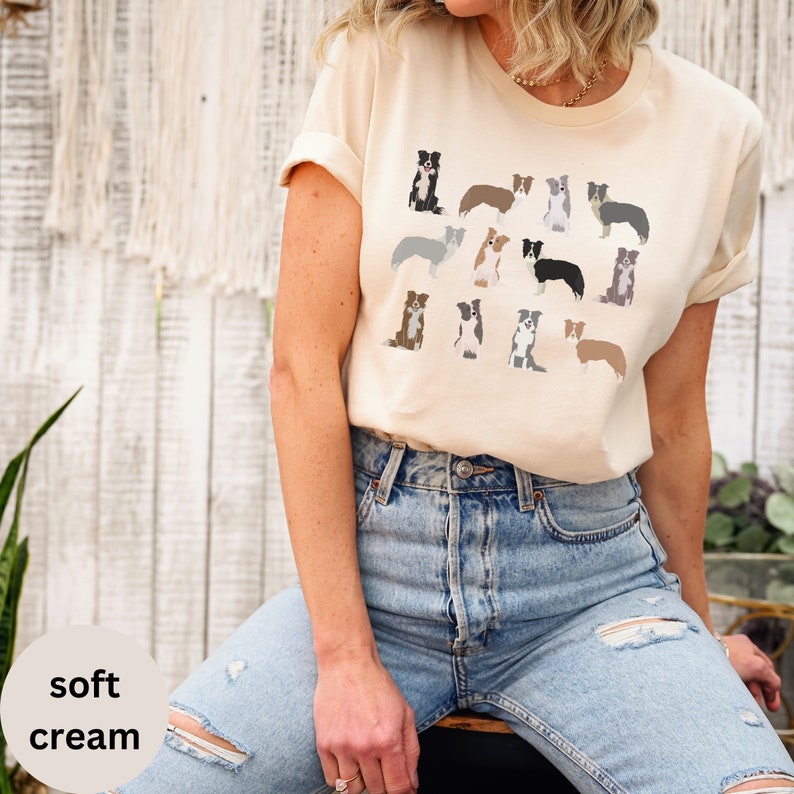 Pode incluir: Uma camiseta bege macia com um padr&atilde;o de border collies de v&aacute;rias cores. A camiseta est&aacute; sendo usada por uma pessoa com jeans azul.