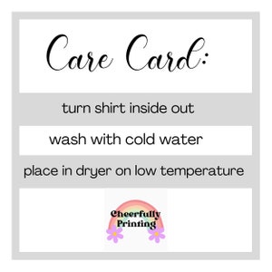 K&ouml;nnte beinhalten: Pflegekarte mit Anweisungen zum Waschen eines Shirts: Shirt auf links drehen, mit kaltem Wasser waschen und in den Trockner bei niedriger Temperatur geben. Die Karte hat eine Regenbogengrafik mit dem Text "Cheerfully Printing".
