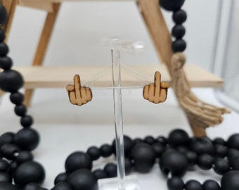 Pode incluir: Um par de brincos de madeira em forma de dedo do meio. Os brincos estão em um expositor.