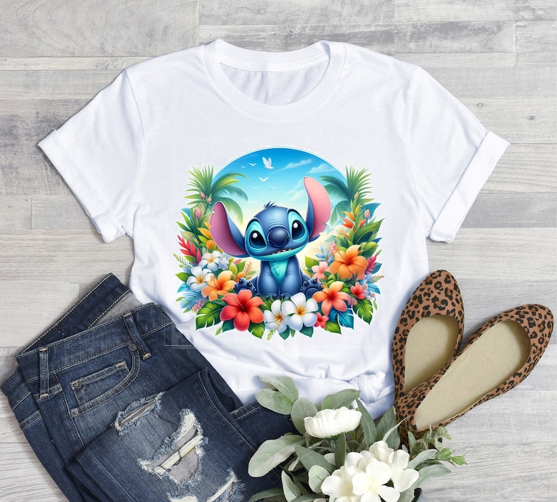 May include: White t-shirt with a blue Stitch character from Lilo & Stitch. Stitch is surrounded by tropical flowers and palm trees. The background is a blue sky with white clouds.