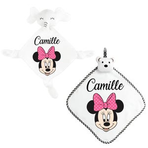 May include: Two white baby security blankets. One features an elephant head, the other a bear head. Both have a Minnie Mouse graphic with a pink polka dot bow, the name "Camille", and a black and white checkered border.