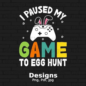Könnte beinhalten: Ein schwarzer Ziegelhintergrund mit einer weißen Grafik, auf der "I paused my game to egg hunt" steht. Die Grafik zeigt einen grün-orange-gelben Gamecontroller mit Hasenohren oben drauf. Der Text "Designs Png, Pdf, Jpg" befindet sich am unteren Rand der Grafik.