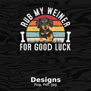 Op de afbeelding: Een retro-stijl grafische afbeelding met een teckel voor een zonsondergang. De tekst luidt "Rub My Weiner For Good Luck".
