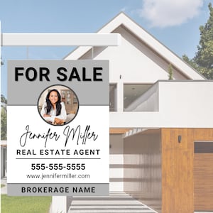 May include: A real estate sign with a grey and white background. The sign reads "FOR SALE" in black text. A photo of a woman is in a circle in the middle of the sign. The text below the photo reads "Jennifer Miller REAL ESTATE AGENT 555-555-5555 www.jennifermiller.com BROKERAGE NAME".