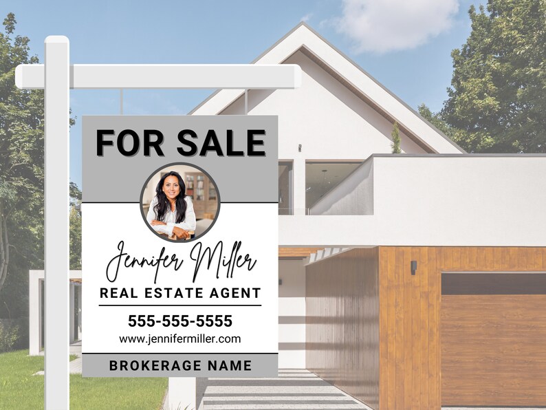 May include: A real estate sign with a grey and white background. The sign reads "FOR SALE" in black text. A photo of a woman is in a circle in the middle of the sign. The text below the photo reads "Jennifer Miller REAL ESTATE AGENT 555-555-5555 www.jennifermiller.com BROKERAGE NAME".