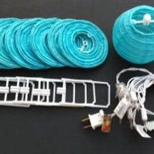 May include: A collection of turquoise paper lanterns and string lights. The lanterns are in a variety of shapes, including round and flat, with a white plastic frame and a plug-in power cord. The string lights have small white bulbs.