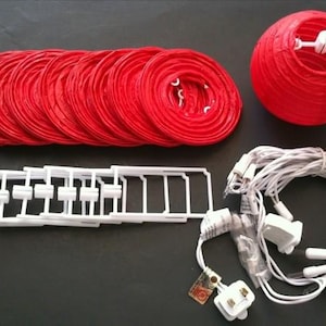 May include: A red paper lantern kit, including multiple red paper lanterns, white support frames, and a string of white lights. The kit also includes a red assembled lantern. The lanterns are designed for decorative purposes.