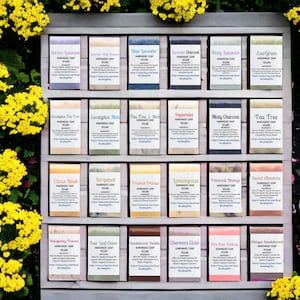 May include: A wooden shelf display with 24 bars of handmade vegan soap. The soaps are arranged in four rows of six bars each. The soaps are labeled with different scents, including Lavender, Tea Tree, Citrus Blast, and Bergamot.