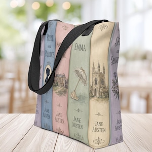 Op de afbeelding: Een draagtas met zwarte stoffen hengsels voorzien van een verticale boekenrugprint. Het ontwerp toont pastelkleurige panelen met Jane Austen-titels zoals Pride and Prejudice, Emma en Sense and Sensibility, vergezeld van illustraties van een landhuis, een parasol en een kathedraal.