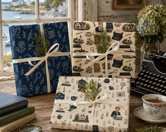 May include: Three rectangular gift boxes wrapped in patterned paper featuring illustrations of lighthouses, typewriters, magnifying glasses, and floral motifs. Each box is tied with a cream-coloured ribbon and adorned with a small sprig of green foliage.