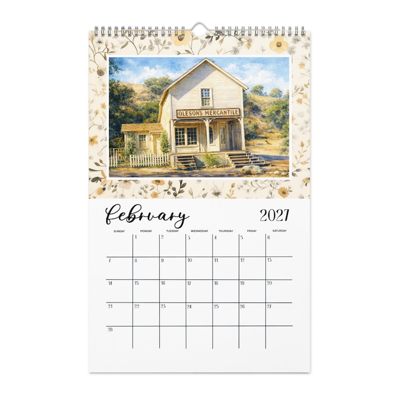 May include: A wall calendar for February 2021 featuring a top illustration of a wooden building labeled Olesons Mercantile. The calendar has a cream-colored border with a delicate brown floral pattern and a white grid for the month's dates.