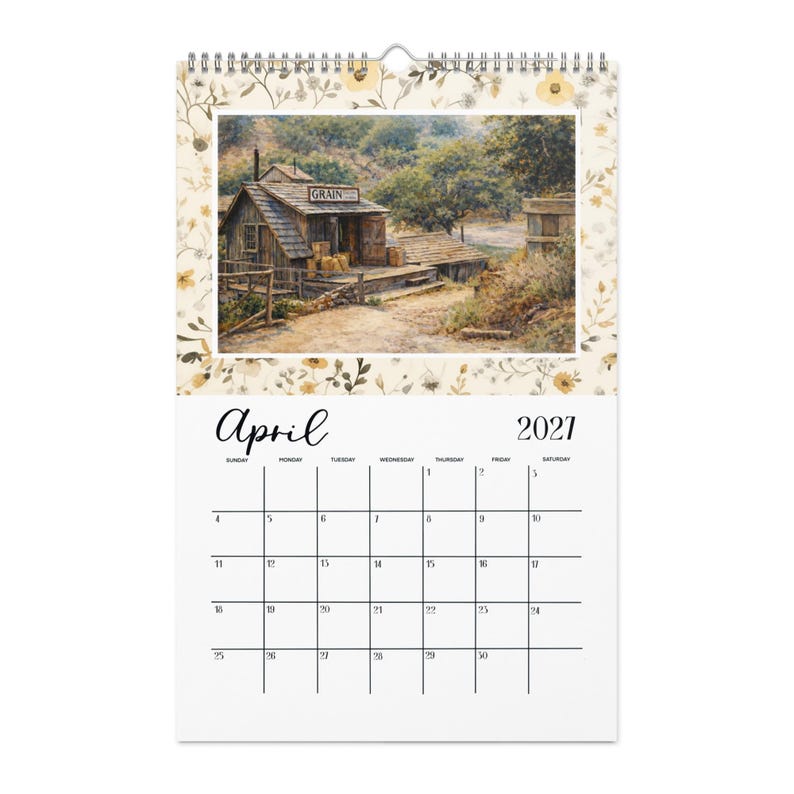 May include: A wall calendar for April 2021 featuring a painting of a rustic wooden grain building with a sign reading GRAIN. The border is decorated with a pattern of small yellow flowers and green leaves on a cream background with a metal spiral binding.