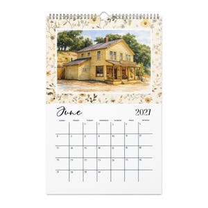May include: A wall calendar for June 2021 featuring a watercolor illustration of a yellow two-story building with a porch and the sign Nellie's Tavern. The top border has a floral pattern in shades of beige, brown, and yellow on a cream background.