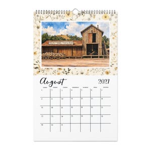 May include: A wall calendar for August 2021 featuring a watercolor illustration of a wooden building labeled Walnut Grove Feed & Seed. The scene includes a stack of burlap sacks, a wooden staircase, and a blue sky with clouds, framed by a floral border.