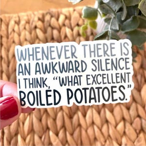 May include: A white sticker with the text "WHENEVER THERE IS AN AWKWARD SILENCE I THINK, 'WHAT EXCELLENT BOILED POTATOES.'" in grey and black. The sticker is held against a woven background.
