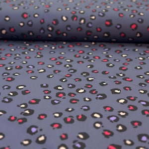 Könnte beinhalten: Nahaufnahme eines blauen Stoffes mit einem weißen, rosa und violetten Leopardenmuster.