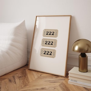 May include: A framed print with three brown paper tickets with the number 222 printed in black on each ticket. The tickets are arranged vertically in a row.
