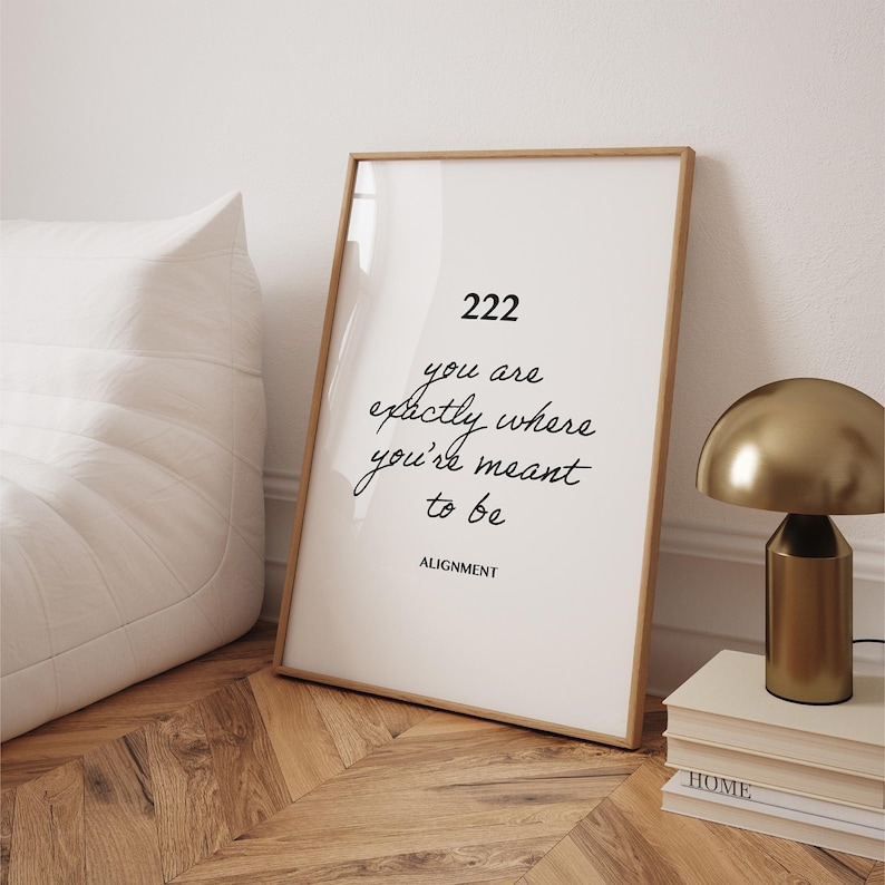 May include: A white framed print with the text "222 you are exactly where you're meant to be ALIGNMENT" in black cursive font.