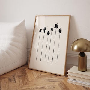 Puede incluir: Una impresión en blanco y negro de palmeras en un marco de madera. La impresión está sobre un fondo crema y las palmeras están silueteados contra el fondo.