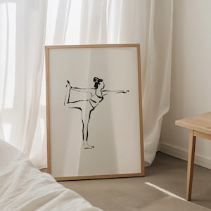 May include: A framed art print featuring a black line drawing of a person in a yoga pose. The artwork is set against a cream-colored background within a light brown wooden frame. The image is displayed in a room with white curtains.