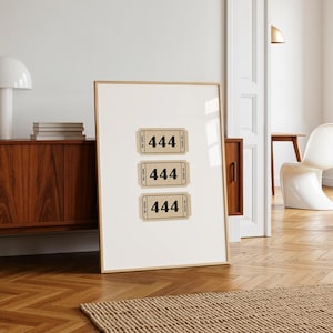 Könnte beinhalten: Ein gerahmter Druck mit drei Tickets im Vintage-Stil, die jeweils die Nummer "444" zeigen. Die Tickets sind beige mit schwarzem Text und einem dekorativen Rand. Der Rahmen ist hellbraun, und der Druck lehnt an einer weißen Wand.