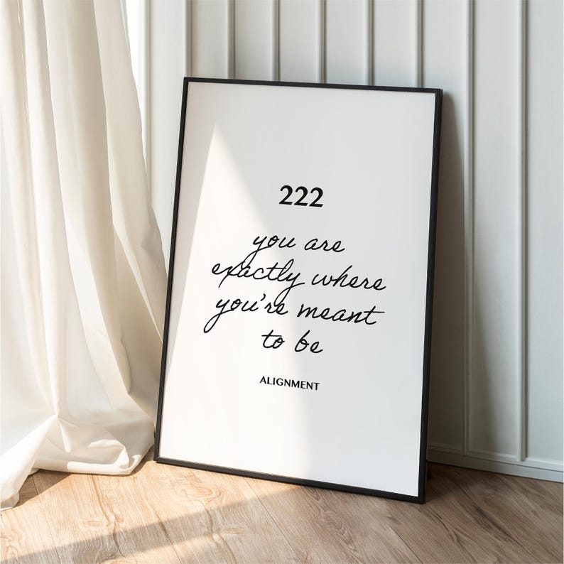 May include: A black framed poster with white background and black text that reads "222 you are exactly where you're meant to be ALIGNMENT".