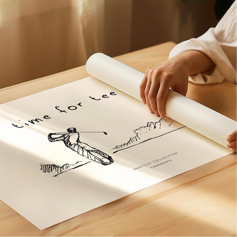 May include: A rolled-up white poster with the text "Time for Tee" and a sketch of a golfer swinging a club. The poster is from the "Sketchy Collection" by Tinksprints. The poster is being unrolled on a wooden surface.