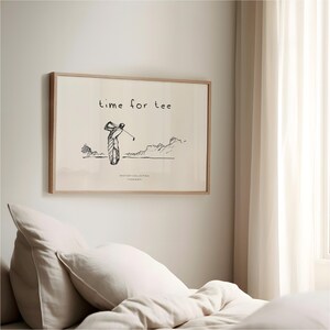 May include: A framed print with a golf theme. The artwork features a sketch of a golfer mid-swing, with the words "time for tee" above. The print is in a light wood frame and hangs on a white wall.