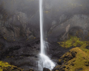 Könnte beinhalten: Ein nebliger Wasserfall stürzt von einer felsigen Klippe herab und erzeugt eine dramatische Szene. Das Wasser fließt über mit Moos bedeckte Felsen und erzeugt ein Gefühl der Ruhe.