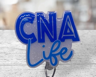 May include: A white and blue glitter badge holder with the text "CNA life" in blue lettering.