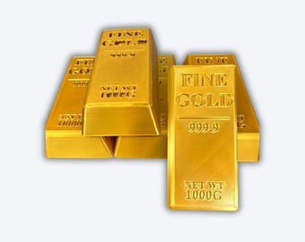 May include: Several gold bars are stacked, with one prominently displayed. The bars are labeled "FINE GOLD" and "999.9", indicating high purity. Each bar is marked with "NET WT 1000G". The image showcases a collection of valuable bullion.