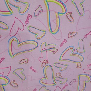 May include: Pink fabric with a repeating pattern of colorful hearts and the word "Barbie" written in pink.