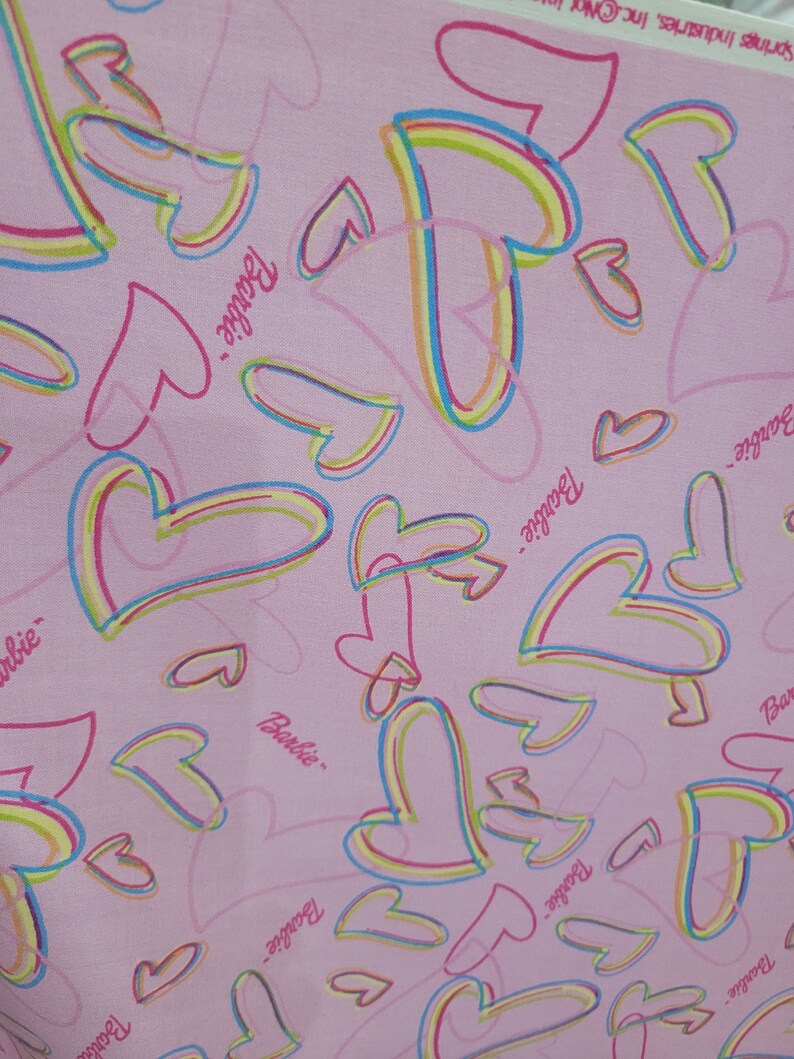 May include: Pink fabric with a repeating pattern of colorful hearts and the word "Barbie" written in pink.