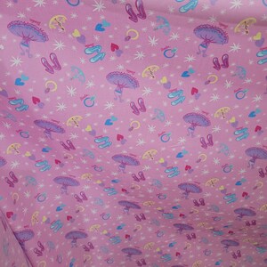 May include: Pink fabric with a repeating pattern of ballet shoes, rings, hearts, and parasols. The word "Barbie" is printed throughout the design. The fabric has a soft, flowing appearance.