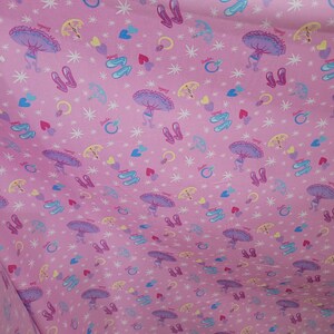 May include: Pink fabric featuring a repeating pattern of ballet shoes, parasols, hearts, rings, and stars. The design includes the word "Barbie". The overall theme is a whimsical, girly design.